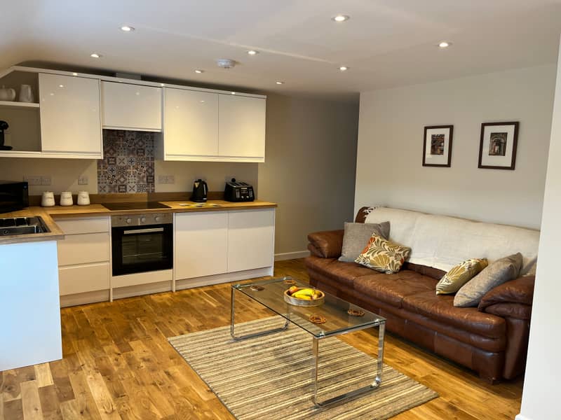 Modern white kitchen with patterned tile splashback, opening onto the sitting area